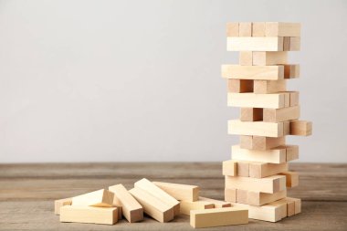 Ahşap Jenga oyununda iş riski kavramı. Gri arkaplanda tahta bloklar
