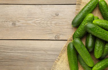 Gri ahşap arka planda çuval bezli taze salatalıklar. Üst görünüm