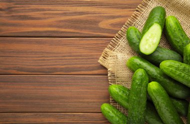 Kahverengi ahşap arka planda çuval bezli taze salatalıklar. Üst görünüm