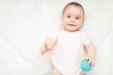Yatakta duyusal topla oynayan tatlı bir bebek. Üst görünüm