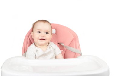 Mutlu bir bebek bebek beyaz arka planda izole edilmiş yüksek bir sandalyede oturuyor.