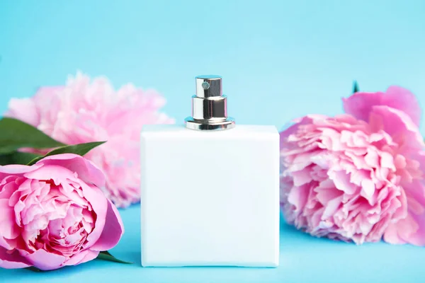 Witte Fles Parfum Met Roze Bloemen Blauwe Achtergrond Met Kopieerruimte — Stockfoto