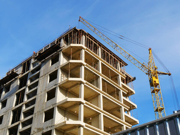 Construction crane and concrete building under construction agai