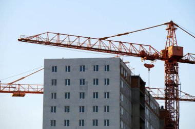Beton bina yapım aşamasındadır. Şantiye. Binanın yakınında iki kule vinçler.