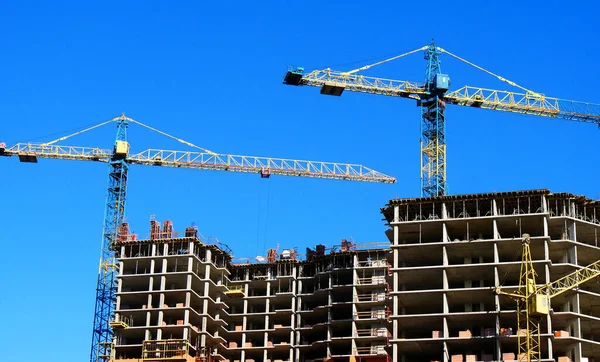 Beton bina yapım aşamasındadır. Şantiye. Binanın yakınında iki kule vinçler.