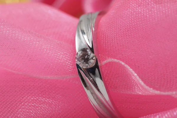 粉色布上镶有钻石的白色金订婚戒指为背景 — 图库照片