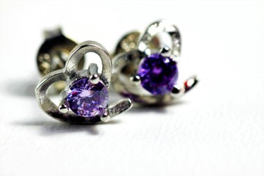 Mor kristal taşlı beyaz altın kalp şeklindeki kulak şeklindeki yakın plan çekimleri.