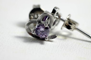 Mor kristal taşlı beyaz altın kalp şeklindeki kulak şeklindeki yakın plan çekimleri.