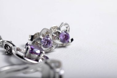 Mor kristal taşlı beyaz altın kalp şeklindeki kulak şeklindeki yakın plan çekimleri.