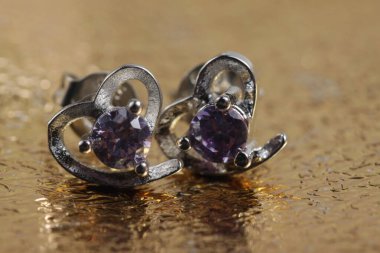 Mor kristal taşlı beyaz altın kalp şeklindeki kulak şeklindeki yakın plan çekimleri.