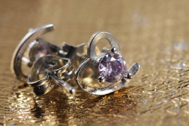 Mor kristal taşlı beyaz altın kalp şeklindeki kulak şeklindeki yakın plan çekimleri.