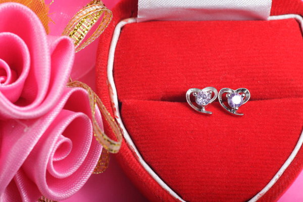 Close ups shot of white golden heart shaped ear stud with purple crystals gem