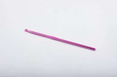 İzole edilmiş beyaz arka planda örgü örmek için pembe metal örgü kancası.