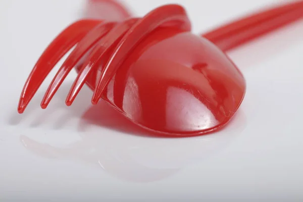Red plastic cutlery on an isolated white background