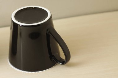 Parlak ahşap bir masada siyah porselen bardak.