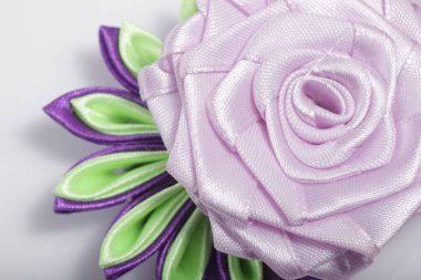 Saten kurdeleden yapılmış mor çiçek broşu.