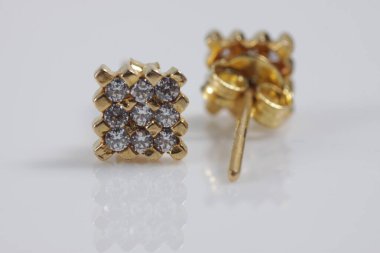 İzole edilmiş bir arka planda kare altın küpeli makro çekim.