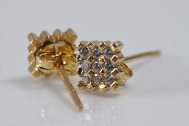 İzole edilmiş bir arka planda kare altın küpeli makro çekim.