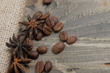 Kavrulmuş kahve çekirdekleri ve halı ve ahşap masa üzerinde yıldız anason resmi.