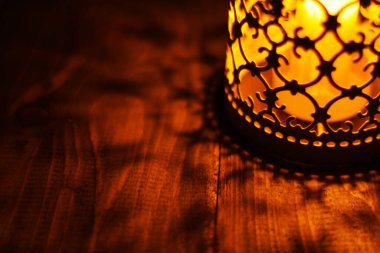 Kırsal bir ahşap masanın üzerindeki mum fenerini yakın plan çek.