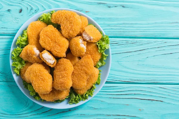 Chicken golden nuggets in plate on rustic background . Unhealthy fast food