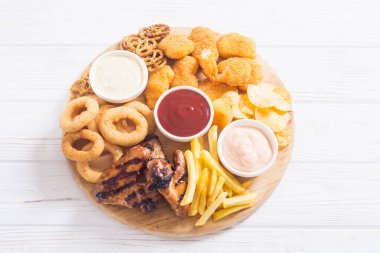 Soğan halkaları, kızarmış kanatlar, patates kızartması ve soslar. Bira tahtası