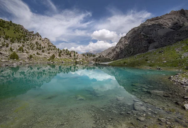 Lago de montanha transparente verde e céu embelezado — Fotografia de Stock