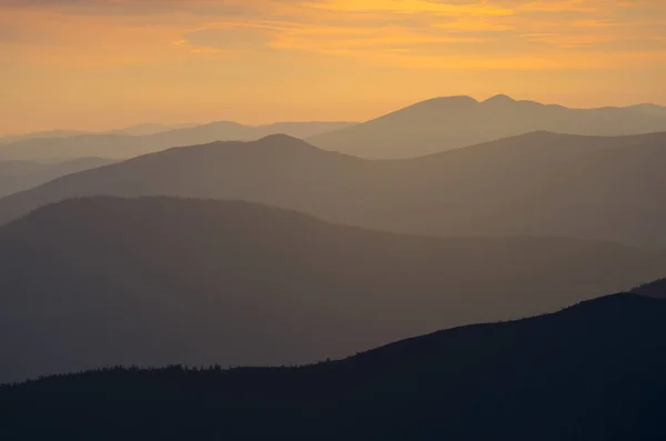 Turuncu gökyüzü arka plan karşı dağlar siluetleri — Stok fotoğraf