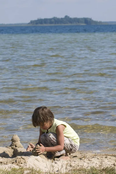 Flicka på stranden bygger torn av sand — Stockfoto