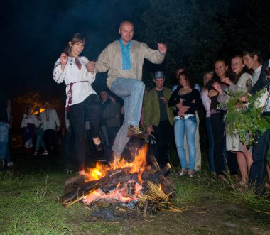 Kiev, Kievskaya oblast / Ukrayna - 07.06.2011. Bayramda şenlik ateşinin üzerinden atlayan bir çift. Ivan Kupala bayram kutlaması. Duygular vahşileşir.
