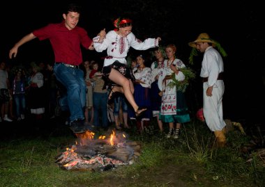 Kiev, Kievskaya oblast / Ukrayna - 07.06.2011. Bayramda şenlik ateşinin üzerinden atlayan genç bir çift. Ivan Kupala bayram kutlaması.