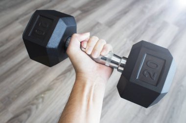 Spor salonunda erkek el siyah halteri tutuyor..