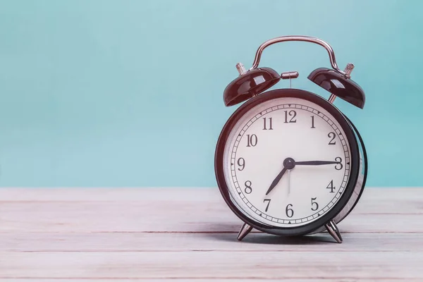 Un reloj despertador negro retro en tablero de madera con fondo verde — Foto de Stock