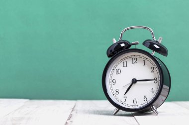 Tahta üzerinde yeşil arka planı olan bir Siyah Retro alarm saati