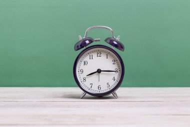 Tahta üzerinde yeşil arka planı olan bir Siyah Retro alarm saati