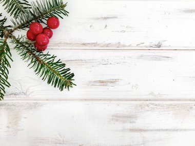 Beyaz ahşap bir arka planda Çam dalları ve kırmızı ahşap elmalı Noel kartı
