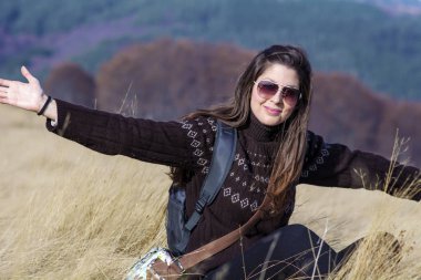 beautiful young woman sitting and posing on field background