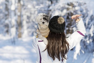 Kışlık şapkalı esmer bir kadının portresi kucağında sevimli bir köpek tutuyor.