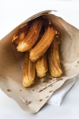 Lezzetli churros beyaz arka planda kese kağıdında kızartılmış.