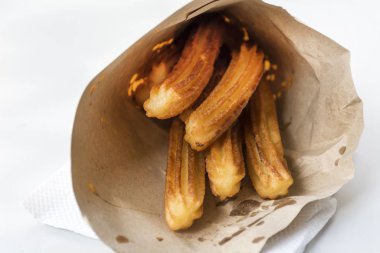Lezzetli churros beyaz arka planda kese kağıdında kızartılmış.