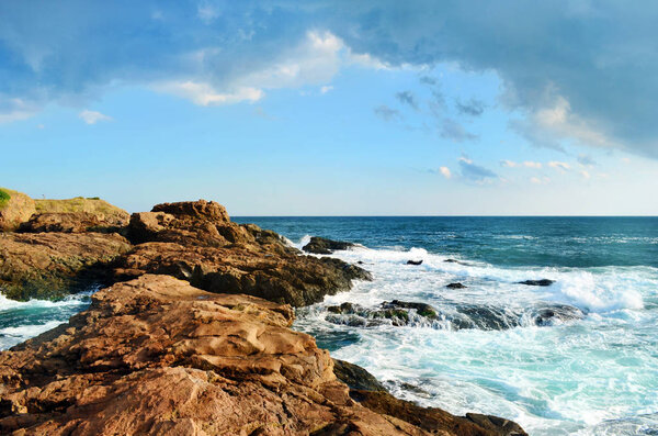 beautiful view of sunny beach with waves and big stones 