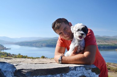 Genç adam Beyaz Havan Köpeğiyle seyahat ediyor.