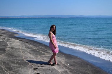 Mutlu Genç Kadın Kara Kum 'la Deniz Sahilinde Yaz Tatili' nin tadını çıkarıyor.