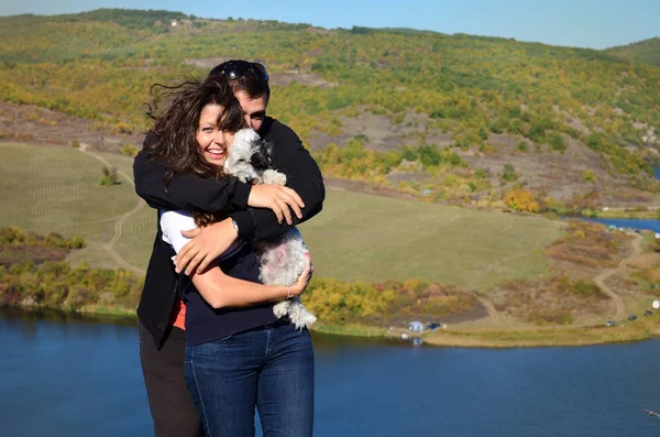 在湖畔的大自然中拥抱爱犬的年轻夫妇 — 图库照片