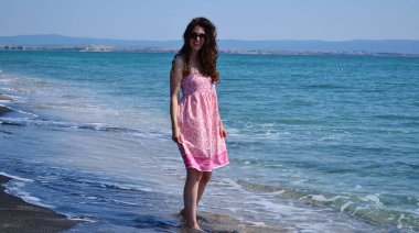 Mutlu Genç Kadın Kara Kum 'la Deniz Sahilinde Yaz Tatili' nin tadını çıkarıyor.