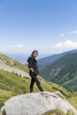 Yaz Dağı 'nın zirvesinde çarpıcı manzaralı mutlu yürüyüşçü kadın. 