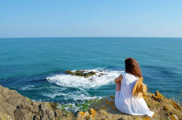 一个人坐在海面上的岩石上的年轻女人 — 图库照片