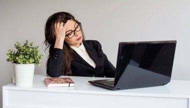 Dizüstü bilgisayarın önünde evden çalışan güzel, yorgun genç bir kadın. 