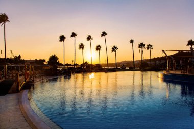 BODRUM, TURKEY -15.05.2018: Palmiye Siluetleriyle Lüks Havuz Üzerinde Güzel Altın Gün Batımı.