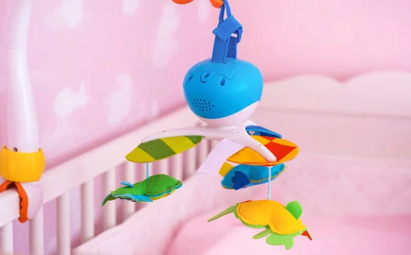 Hanging Toy Attached to a Baby Cot in a Pink Room